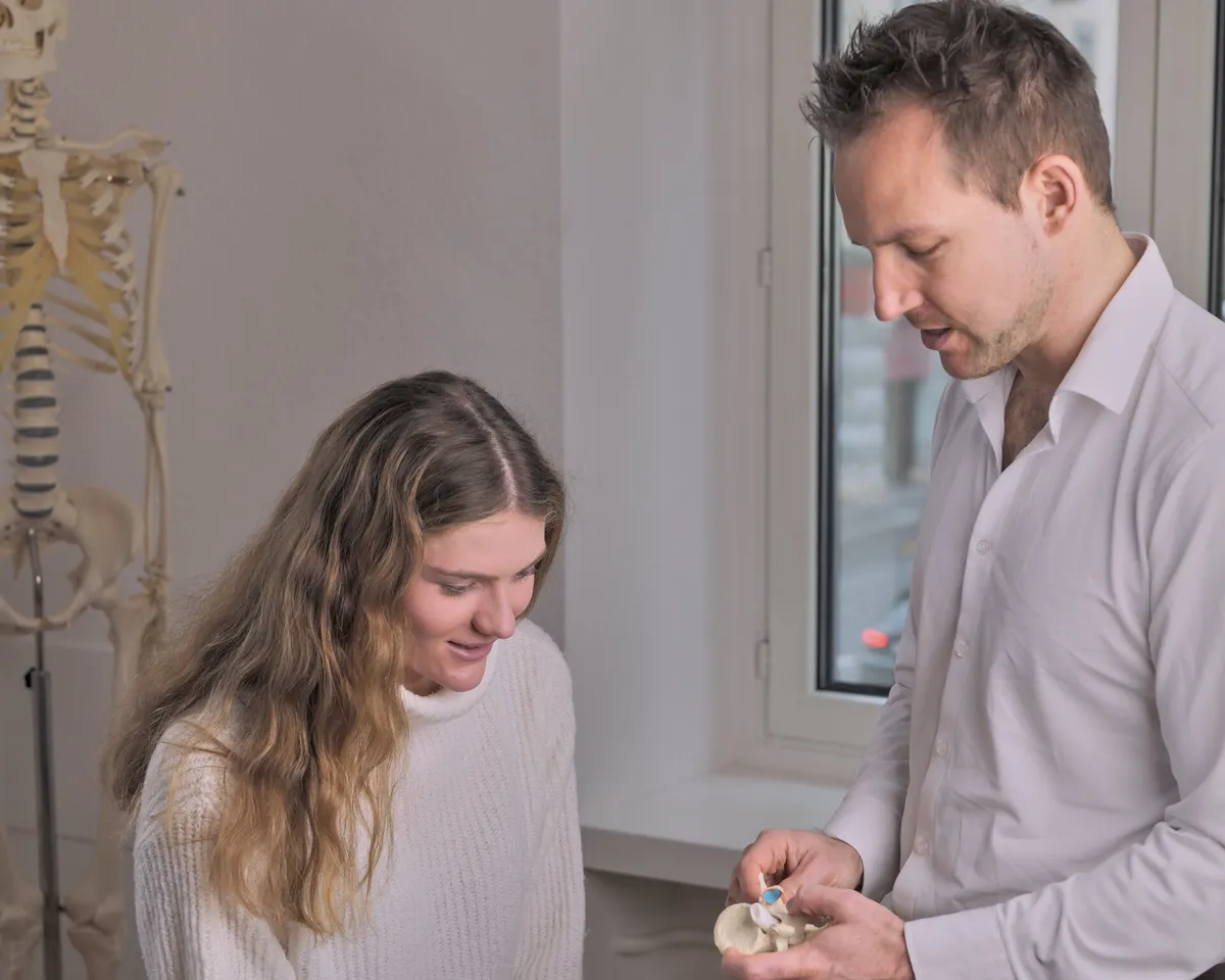 Dr. Florian Senn erklärt einer Patientin anhand eines Becken-Modells das McGill Assessment in der Chiropraktik-Praxis St. Gallen